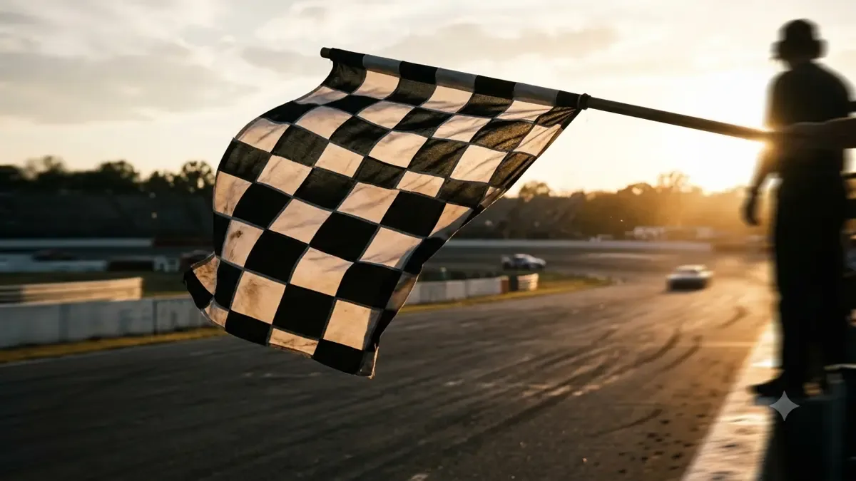 Bandera a cuadros ondeando sobre el asfalto desenfocado de un circuito